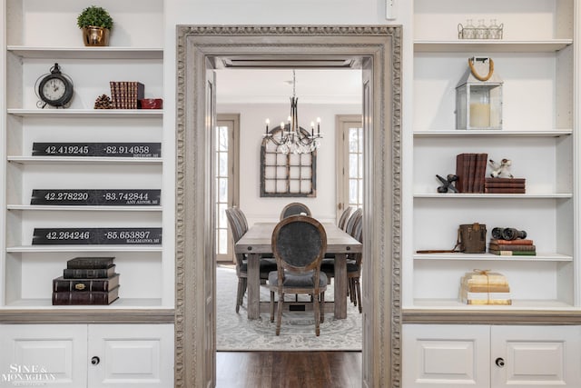 dining space featuring built in features, a chandelier, dark wood finished floors, and crown molding