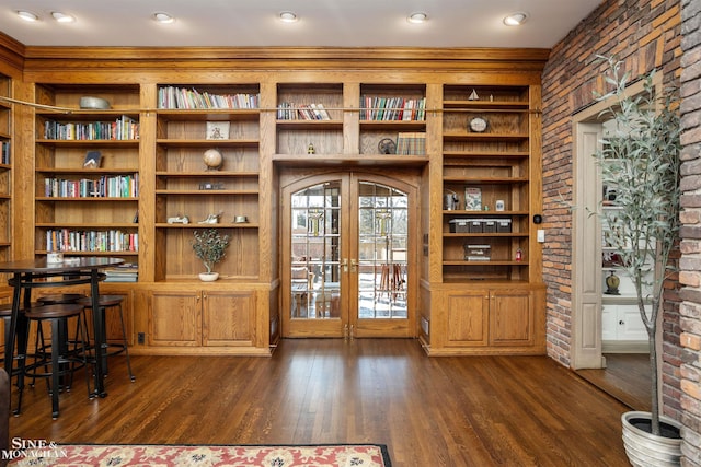 interior space with dark wood-type flooring, french doors, arched walkways, and brick wall