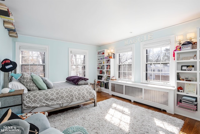 bedroom with radiator and wood finished floors