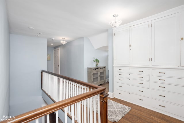 corridor with an upstairs landing, a notable chandelier, and dark wood finished floors