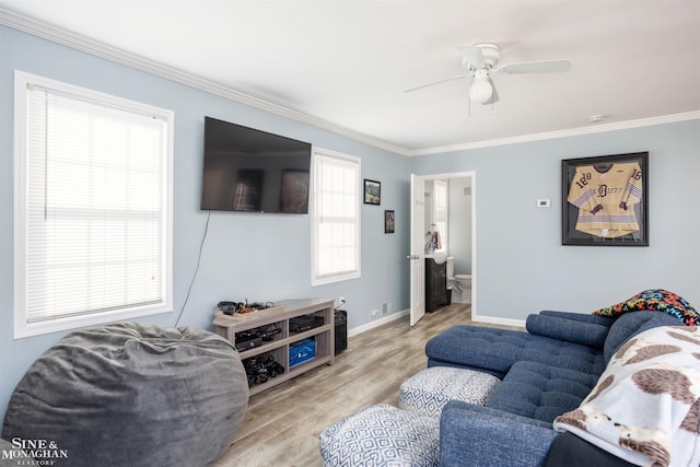 living area featuring ceiling fan, crown molding, baseboards, and wood finished floors