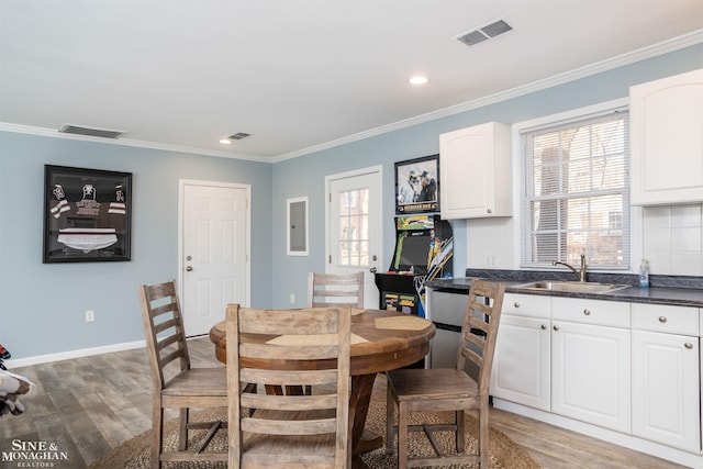 dining space with visible vents, light wood finished floors, and ornamental molding