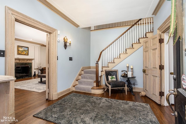 foyer entrance with stairs, baseboards, wood finished floors, and a fireplace