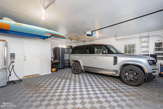 garage with a garage door opener, freestanding refrigerator, and baseboards