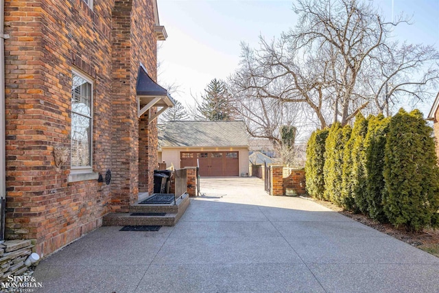 view of side of home featuring brick siding and a detached garage