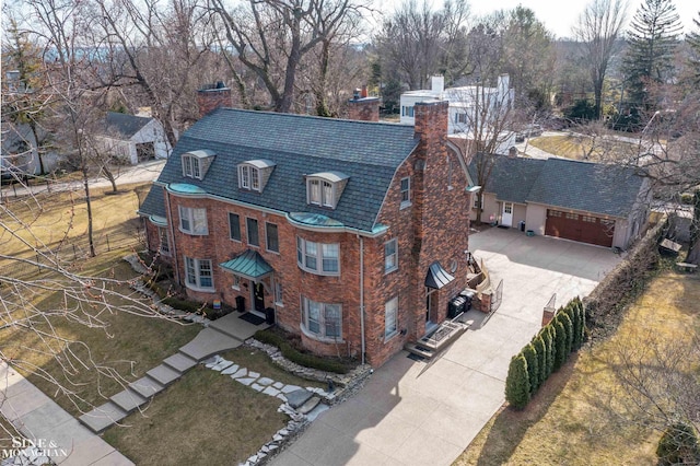 view of front facade featuring brick siding, a high end roof, concrete driveway, a chimney, and an attached garage