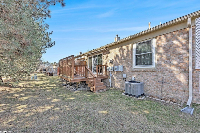 rear view of house featuring a yard, brick siding, and central AC