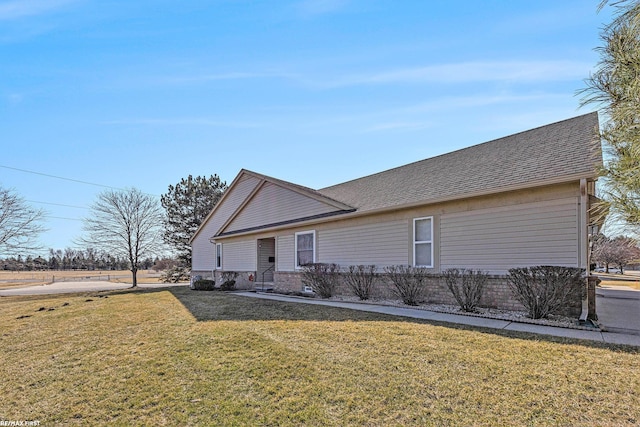 view of front of home with a front lawn, brick siding, and roof with shingles