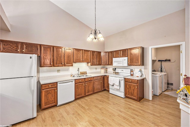 kitchen with white appliances, high vaulted ceiling, light wood-style flooring, light countertops, and washing machine and dryer