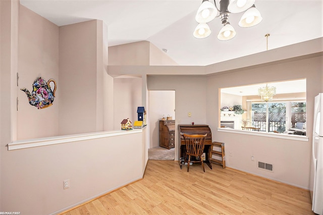 interior space featuring visible vents, lofted ceiling, a notable chandelier, and wood finished floors