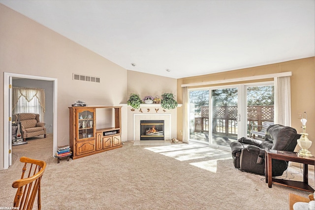 carpeted living area with high vaulted ceiling, visible vents, and a tile fireplace