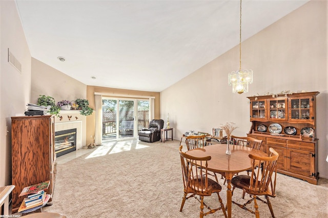 dining room with visible vents, a tiled fireplace, light carpet, an inviting chandelier, and high vaulted ceiling