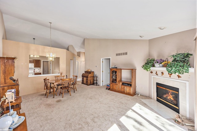 interior space with visible vents, a chandelier, vaulted ceiling, light carpet, and a fireplace