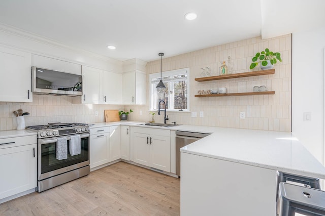 kitchen with a sink, stainless steel appliances, a peninsula, and white cabinets