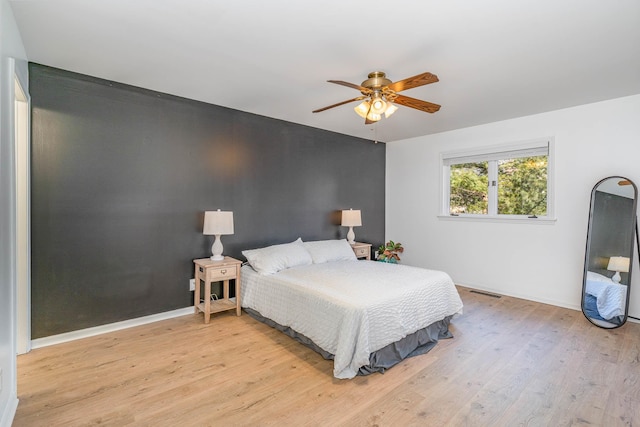 bedroom featuring light wood-type flooring, baseboards, visible vents, and a ceiling fan