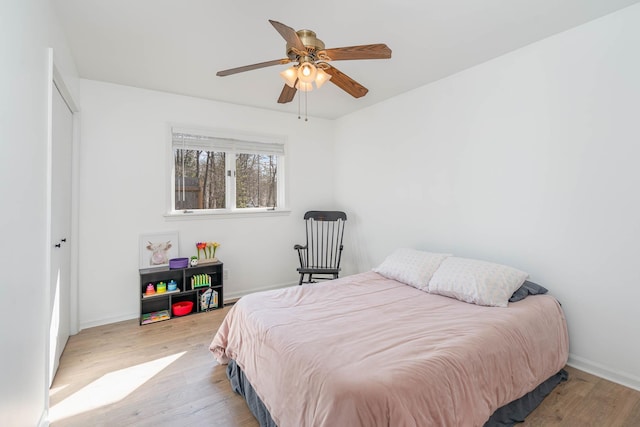 bedroom featuring light wood-style flooring, baseboards, and ceiling fan