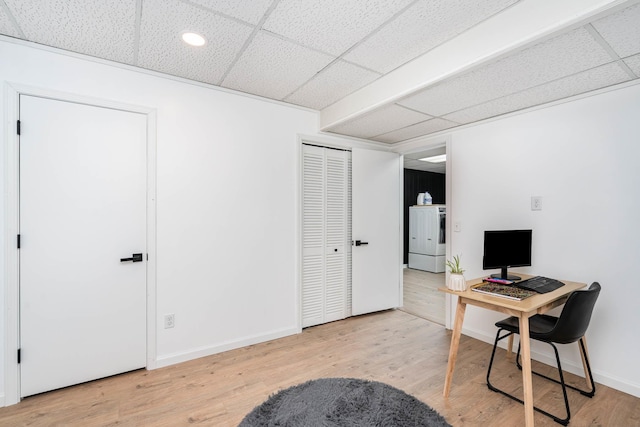 home office with washer / clothes dryer, a paneled ceiling, baseboards, and wood finished floors