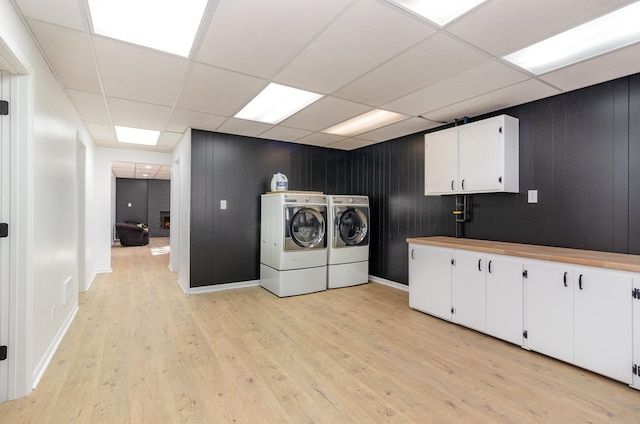 laundry area featuring light wood finished floors, cabinet space, and separate washer and dryer