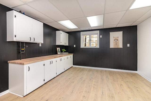 kitchen with a paneled ceiling, light wood-style floors, and white cabinets