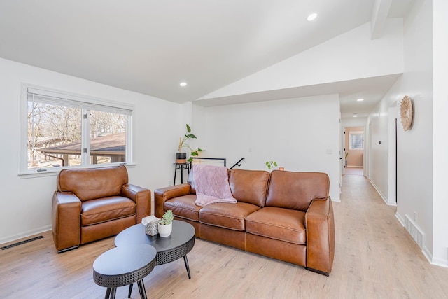 living area with visible vents, light wood-style floors, and vaulted ceiling