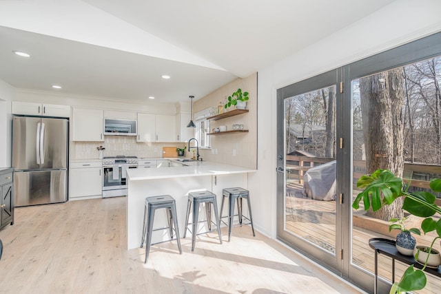 kitchen with a sink, decorative backsplash, light countertops, appliances with stainless steel finishes, and a kitchen breakfast bar