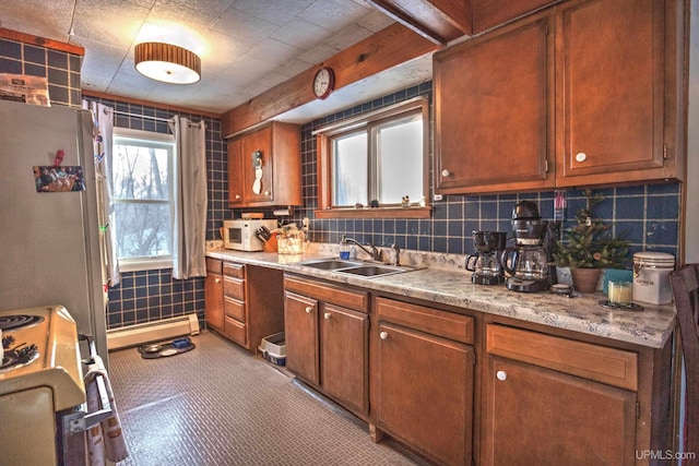 kitchen with range with gas stovetop, white microwave, freestanding refrigerator, a sink, and light countertops