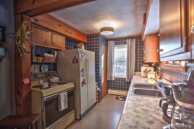 kitchen featuring brown cabinetry, freestanding refrigerator, a sink, light countertops, and range with electric stovetop