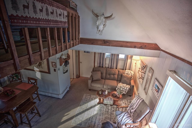 living area featuring carpet, wood walls, and vaulted ceiling