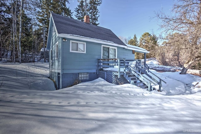 view of front facade featuring a deck, a chimney, and a shingled roof