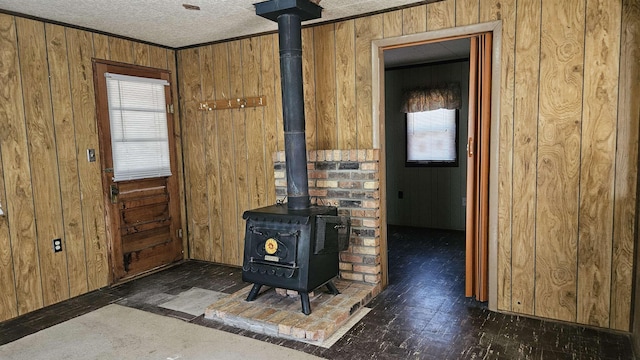 interior details featuring a wood stove, wooden walls, and a textured ceiling