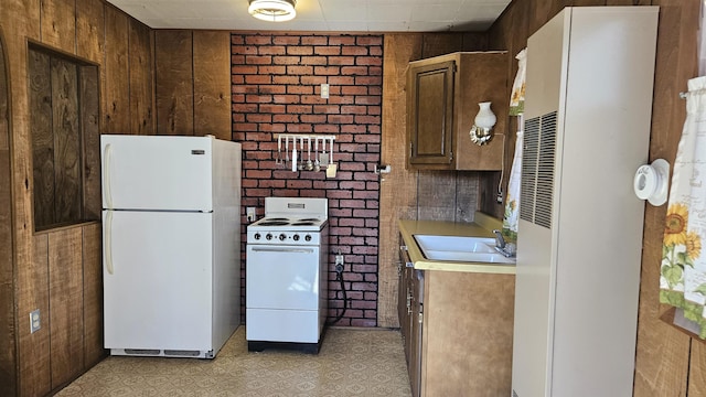 kitchen with white appliances, wooden walls, light floors, a sink, and light countertops