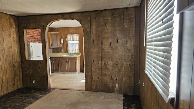 interior space with arched walkways, wooden walls, plenty of natural light, and freestanding refrigerator