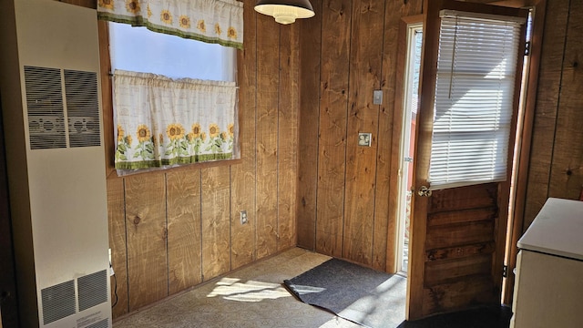 doorway with a heating unit and wood walls