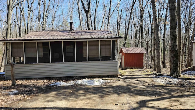 view of side of home with an outdoor structure, a shed, a sunroom, and metal roof