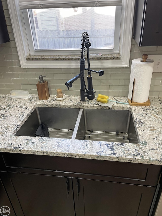 interior details featuring light stone counters, decorative backsplash, and a sink