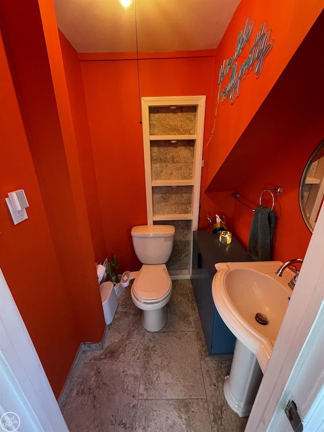 bathroom featuring toilet, baseboards, and a sink