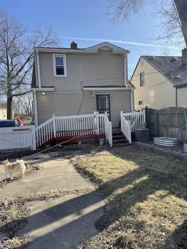 back of property featuring a yard, a deck, a chimney, and fence