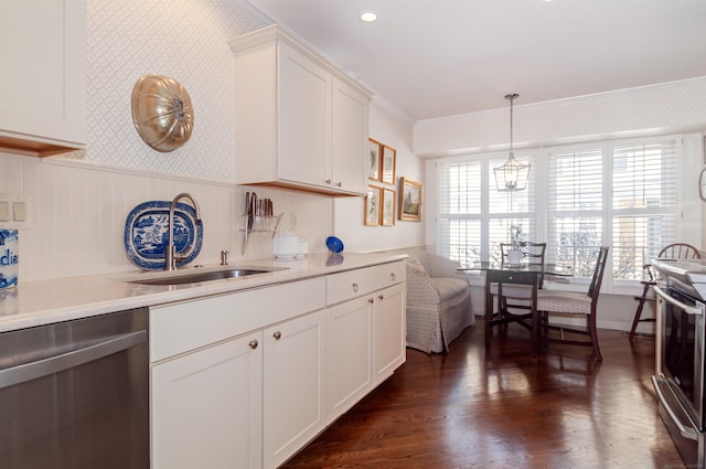 kitchen with a sink, wallpapered walls, white cabinetry, stainless steel appliances, and light countertops