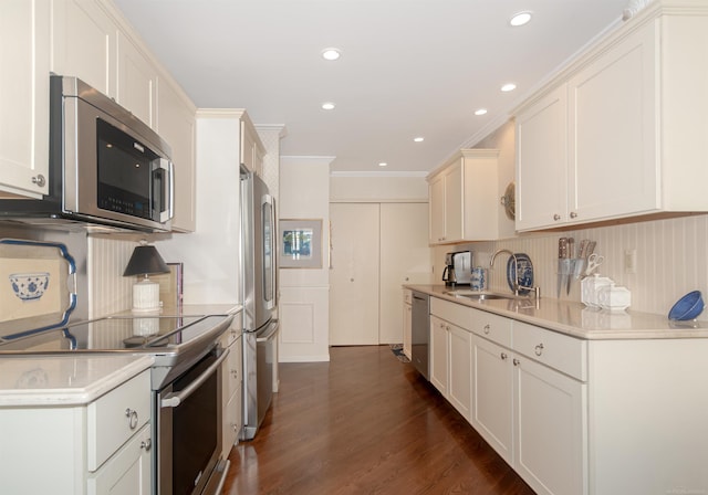 kitchen featuring dark wood finished floors, light countertops, ornamental molding, stainless steel appliances, and a sink