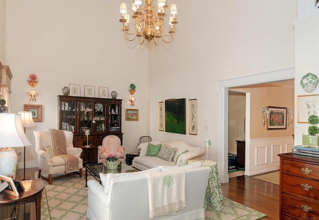 living area featuring a chandelier, wood finished floors, and a towering ceiling