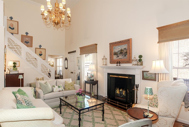 living area with wood finished floors, a high ceiling, a warm lit fireplace, stairs, and crown molding