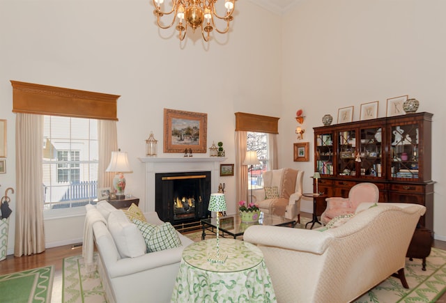 living room with an inviting chandelier, light wood-style floors, a lit fireplace, and a healthy amount of sunlight