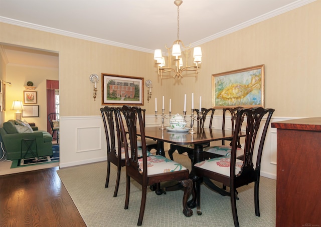 dining space featuring crown molding, dark wood-type flooring, a chandelier, and wainscoting