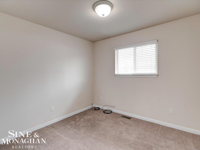 carpeted spare room with visible vents and baseboards