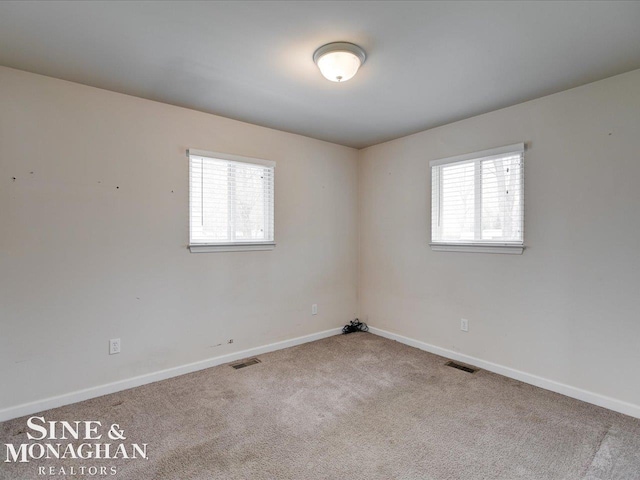 carpeted empty room featuring a wealth of natural light, visible vents, and baseboards