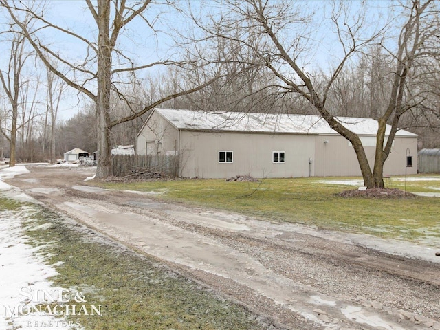 view of property exterior featuring a yard, driveway, an outdoor structure, and a pole building