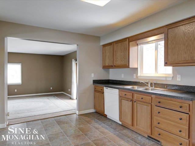 kitchen featuring a sink, plenty of natural light, dark countertops, and white dishwasher