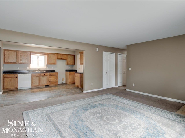 kitchen featuring dishwasher, dark countertops, light colored carpet, and baseboards