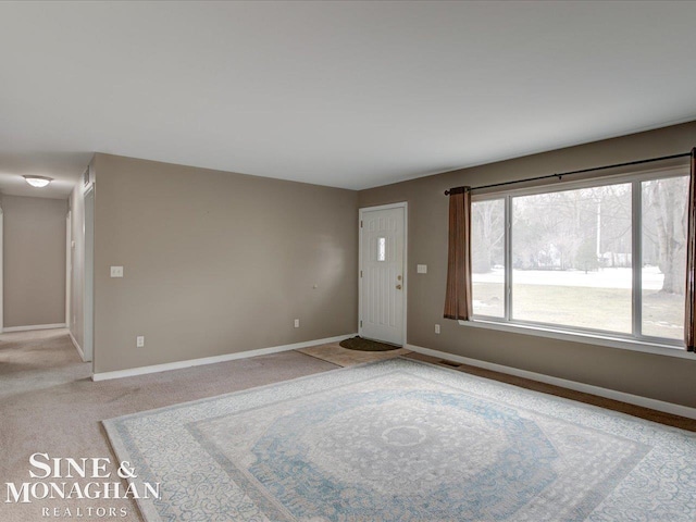 unfurnished living room featuring visible vents, baseboards, and light carpet