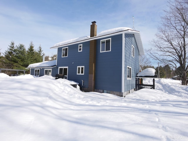 snow covered property featuring a chimney